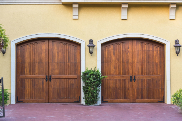 Two wooden garage doors on a yellow building.